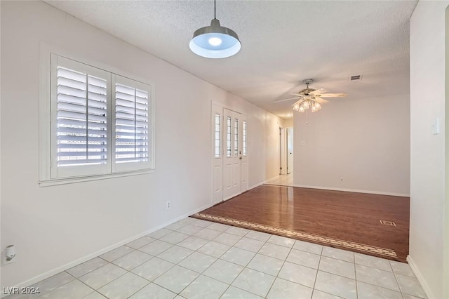 tiled empty room featuring ceiling fan and a textured ceiling