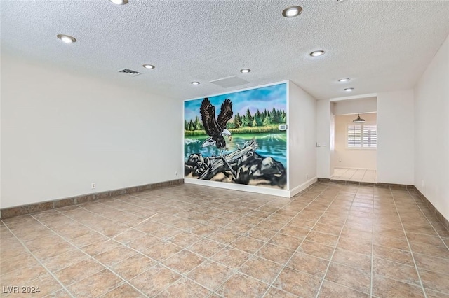 tiled empty room featuring a textured ceiling