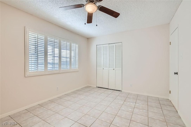 unfurnished bedroom with ceiling fan, a closet, a textured ceiling, and light tile patterned flooring