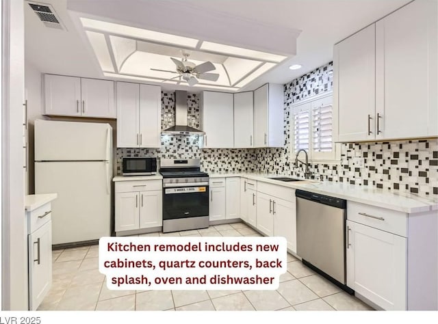 kitchen featuring sink, white cabinetry, stainless steel appliances, a raised ceiling, and wall chimney exhaust hood