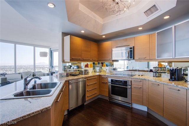 kitchen featuring sink, dark hardwood / wood-style floors, a tray ceiling, a notable chandelier, and stainless steel appliances