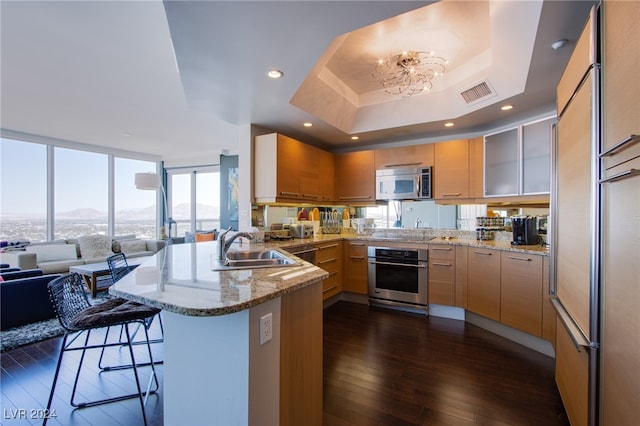 kitchen featuring dark wood-type flooring, sink, a kitchen bar, kitchen peninsula, and stainless steel appliances