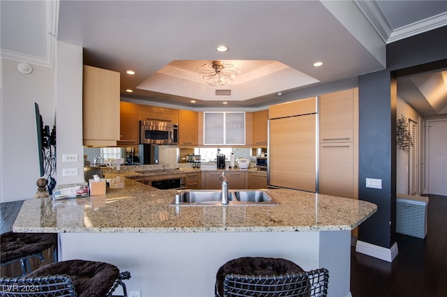 kitchen with sink, dark wood-type flooring, kitchen peninsula, a kitchen bar, and paneled built in fridge