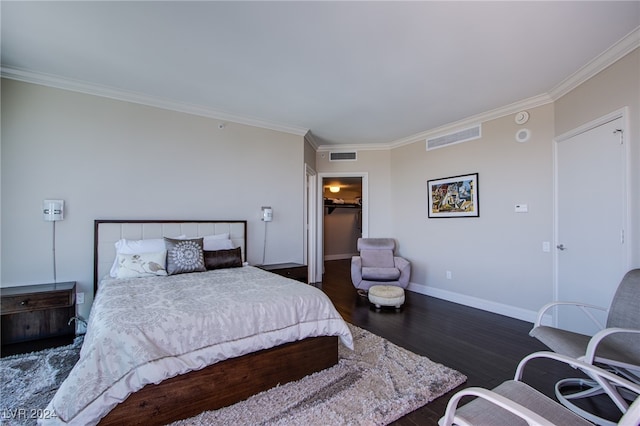 bedroom with a walk in closet, dark hardwood / wood-style flooring, a closet, and ornamental molding