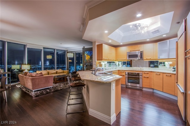 kitchen featuring kitchen peninsula, dark hardwood / wood-style flooring, stainless steel appliances, sink, and a breakfast bar area