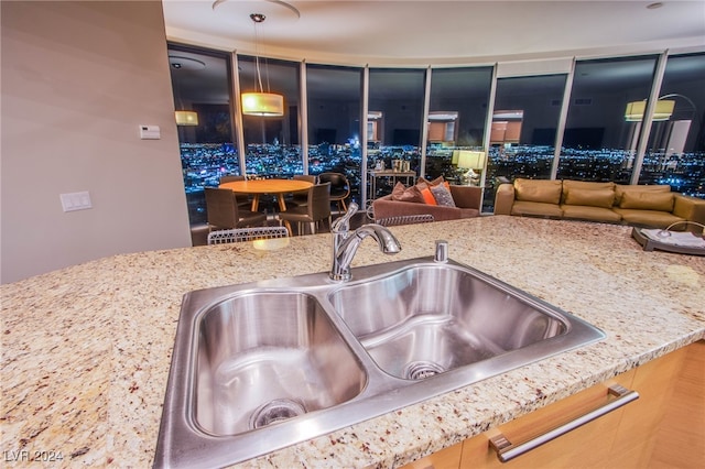 kitchen with decorative light fixtures, light stone counters, and sink