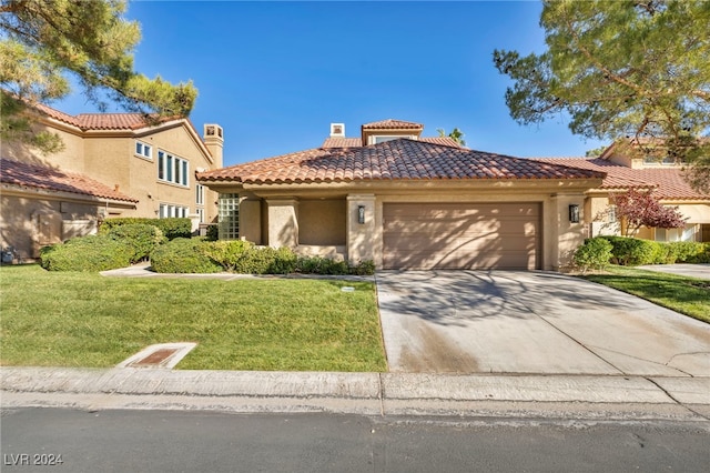 mediterranean / spanish home featuring a front yard and a garage