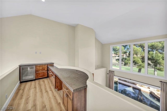 interior space featuring wine cooler, light hardwood / wood-style floors, and lofted ceiling