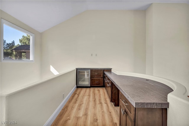 office area featuring wine cooler, light hardwood / wood-style flooring, and lofted ceiling