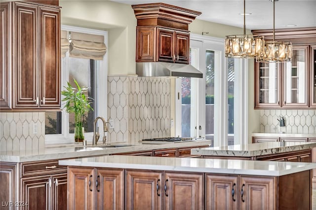 kitchen featuring pendant lighting, sink, tasteful backsplash, a kitchen island, and stainless steel gas cooktop