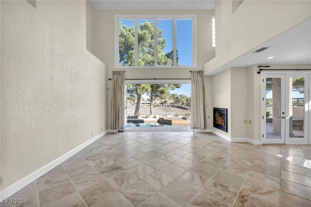 unfurnished living room with french doors and a towering ceiling