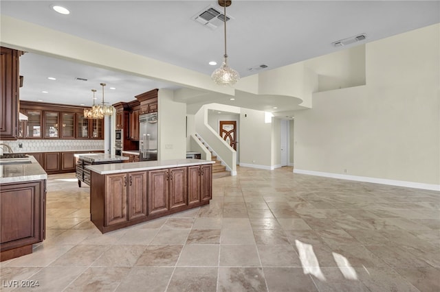 kitchen featuring a center island, sink, built in refrigerator, tasteful backsplash, and decorative light fixtures