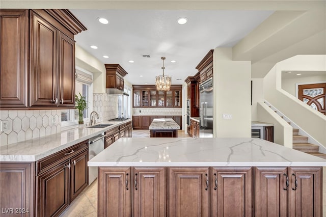 kitchen featuring a center island, sink, decorative backsplash, decorative light fixtures, and light stone counters