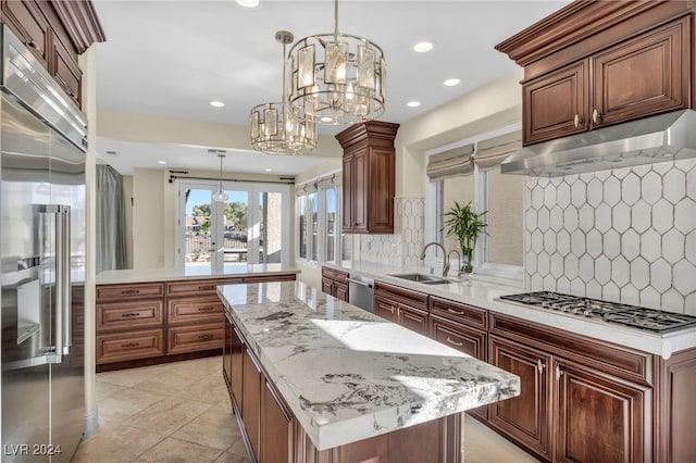 kitchen featuring decorative backsplash, appliances with stainless steel finishes, sink, an inviting chandelier, and a kitchen island