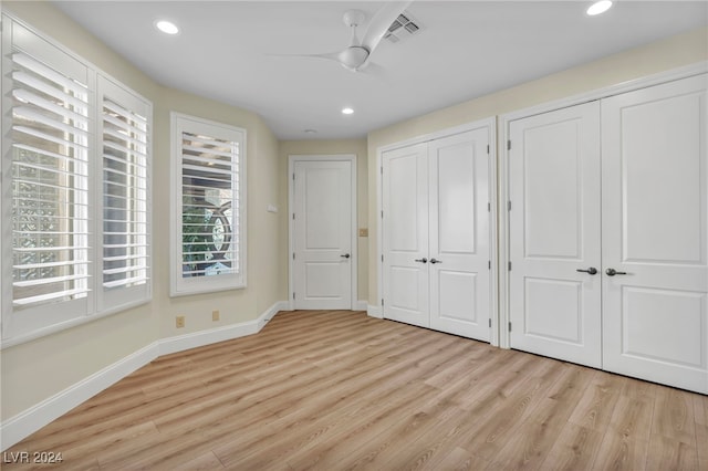 unfurnished bedroom with two closets, light hardwood / wood-style flooring, and ceiling fan