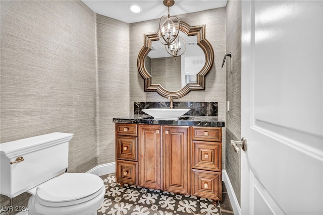 bathroom with tile patterned floors, vanity, an inviting chandelier, and toilet