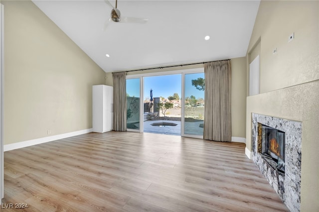 unfurnished living room with a high end fireplace, light hardwood / wood-style floors, high vaulted ceiling, and ceiling fan