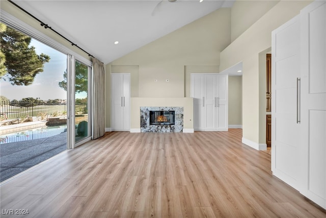 unfurnished living room with light wood-type flooring and high vaulted ceiling