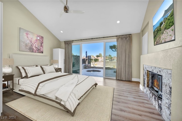 bedroom featuring access to exterior, vaulted ceiling, ceiling fan, a premium fireplace, and light hardwood / wood-style floors