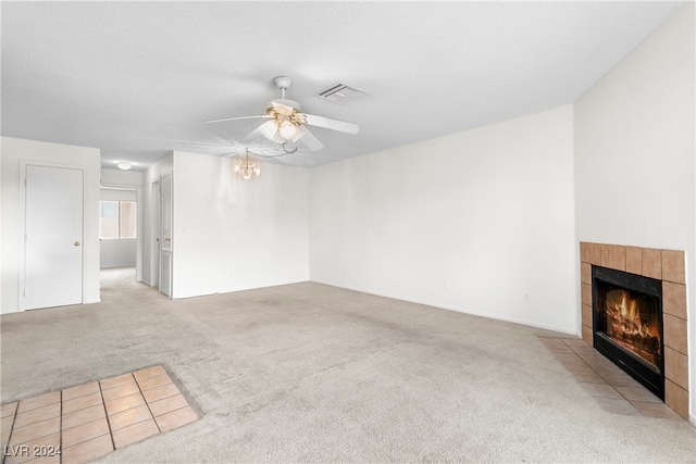 unfurnished living room with a textured ceiling, a fireplace, ceiling fan, and light carpet