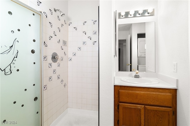 bathroom with stacked washer / dryer, vanity, and tiled shower