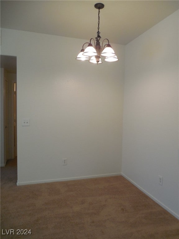 empty room featuring carpet floors and a chandelier