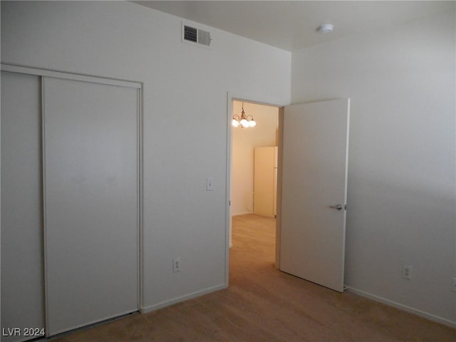 unfurnished bedroom featuring a closet, carpet floors, and an inviting chandelier