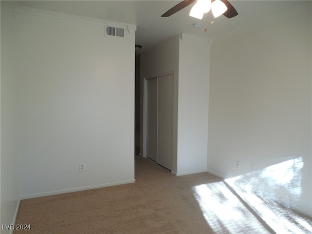 unfurnished room with ceiling fan, light colored carpet, and crown molding