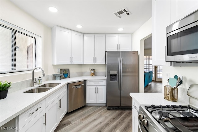 kitchen with light hardwood / wood-style floors, white cabinetry, sink, and appliances with stainless steel finishes