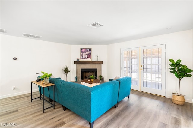 living room with a fireplace, french doors, and light wood-type flooring