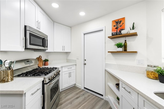 kitchen featuring light hardwood / wood-style floors, light stone counters, white cabinetry, and stainless steel appliances