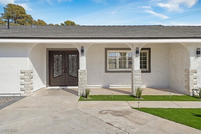 doorway to property featuring a porch and french doors