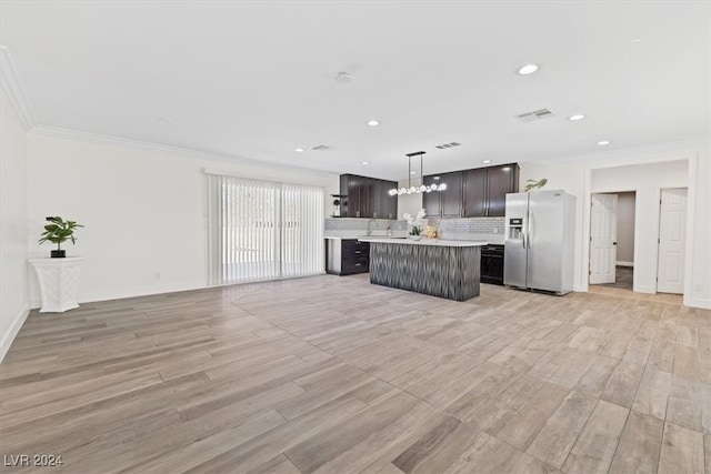 kitchen with pendant lighting, stainless steel refrigerator with ice dispenser, light hardwood / wood-style floors, ornamental molding, and a kitchen island