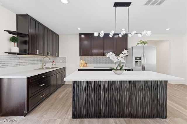 kitchen with a center island, decorative light fixtures, stainless steel refrigerator with ice dispenser, and sink