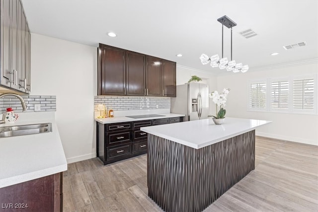 kitchen featuring pendant lighting, sink, stainless steel fridge, ornamental molding, and a kitchen island