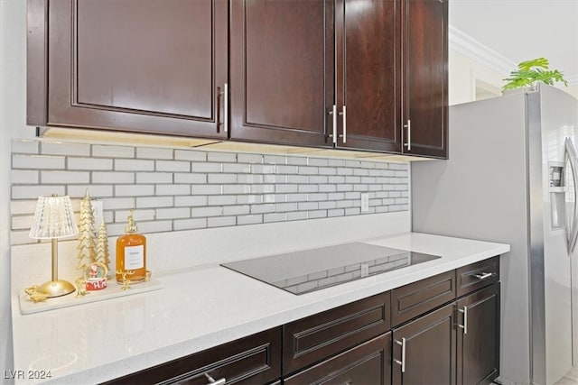 kitchen with decorative backsplash, stainless steel fridge, black electric cooktop, and ornamental molding