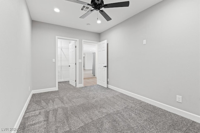 unfurnished bedroom with light carpet, a closet, a spacious closet, and ceiling fan