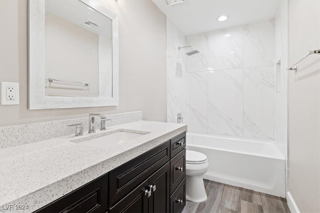 full bathroom with hardwood / wood-style flooring, vanity, toilet, and tiled shower / bath