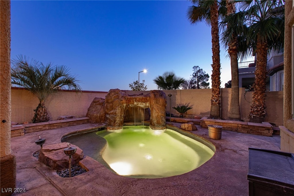 pool at dusk featuring a patio