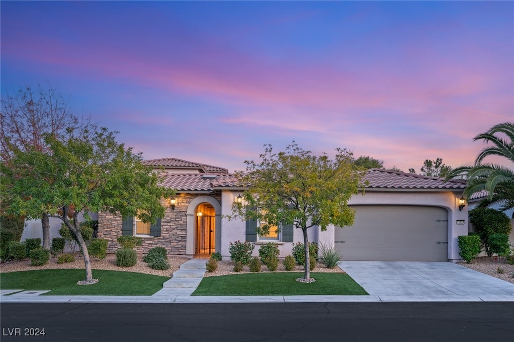 mediterranean / spanish home with a garage and a yard