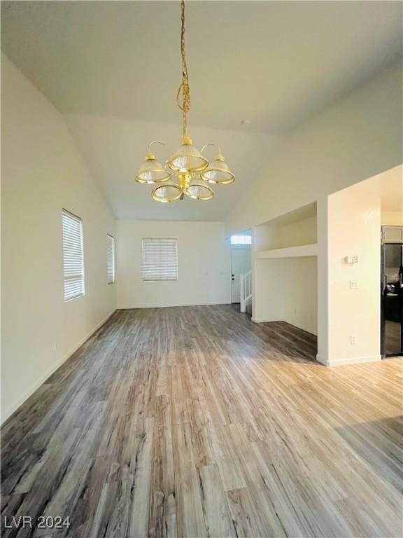 interior space with an inviting chandelier, vaulted ceiling, and hardwood / wood-style flooring