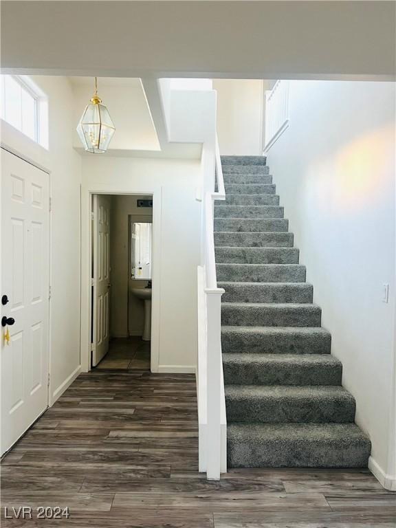 stairs featuring hardwood / wood-style floors and a chandelier