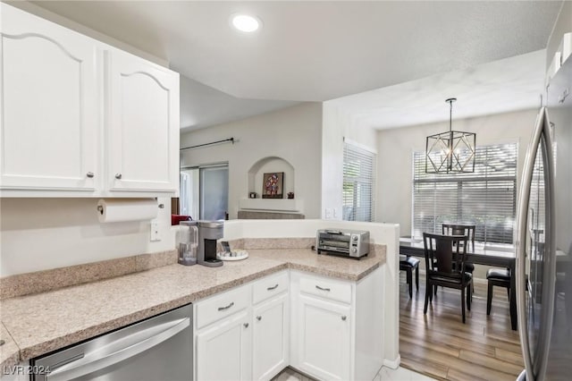 kitchen with stainless steel appliances, an inviting chandelier, pendant lighting, and white cabinetry