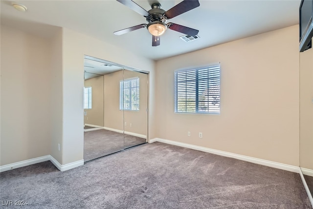 unfurnished bedroom with carpet flooring, ceiling fan, a closet, and multiple windows