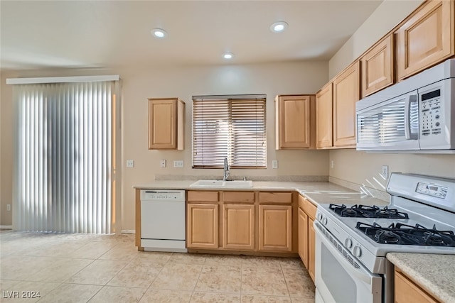 kitchen with light brown cabinetry, white appliances, light tile patterned floors, and sink