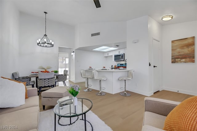 living room with light wood-type flooring, high vaulted ceiling, and a notable chandelier