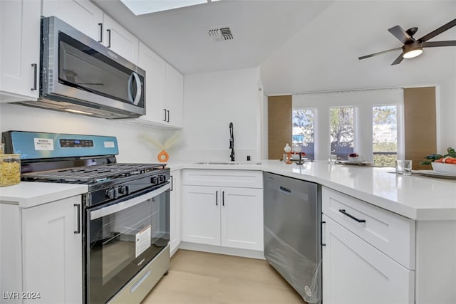 kitchen with kitchen peninsula, stainless steel appliances, white cabinets, and sink