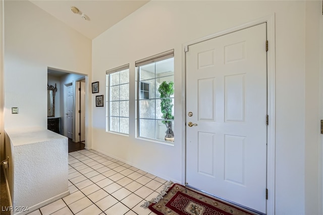 entryway featuring light tile patterned floors and vaulted ceiling