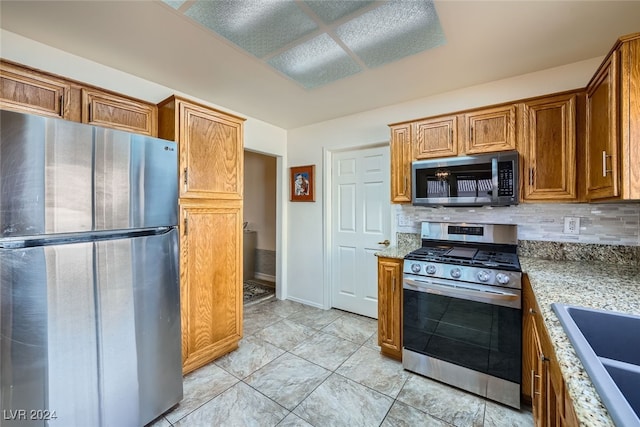 kitchen featuring light stone counters, sink, stainless steel appliances, and tasteful backsplash