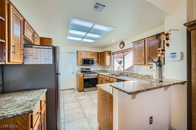 kitchen with sink, light stone countertops, appliances with stainless steel finishes, tasteful backsplash, and kitchen peninsula